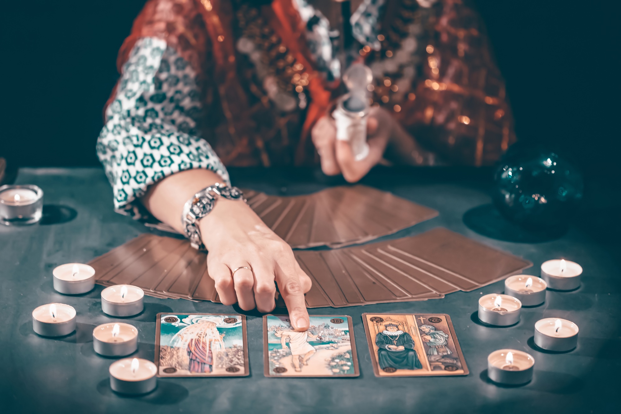 Tarot reader with tarot cards.Tarot cards face down on table near burning candles and crystal ball.